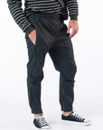 Male model wearing black casual zip pants with hand in pocket