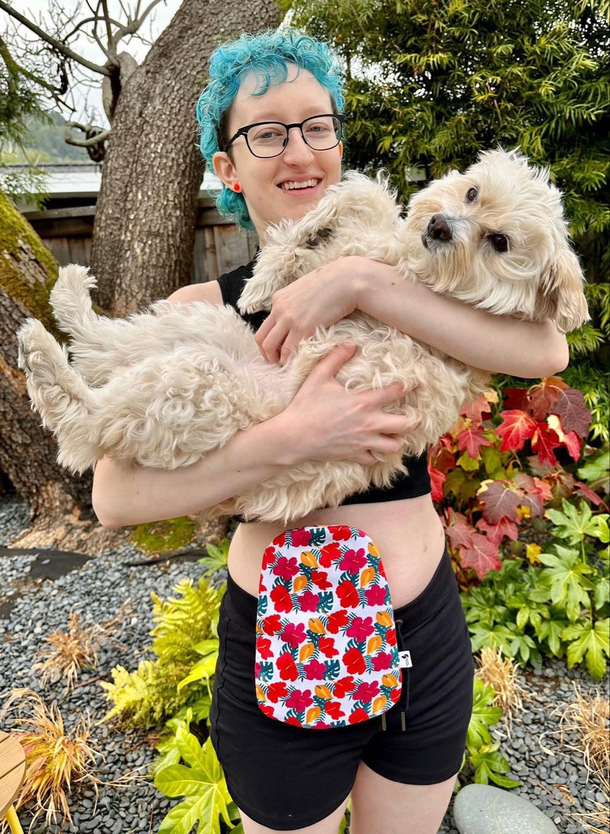 Woman wearing Hibiscus elastic ostomy bag cover holding dog