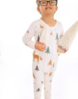 Child standing wearing Thru the Trees G-Tube Pajamas, holding mini tree decorations