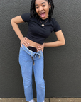 Woman standing against gray wall in black elastic ostomy bag cover