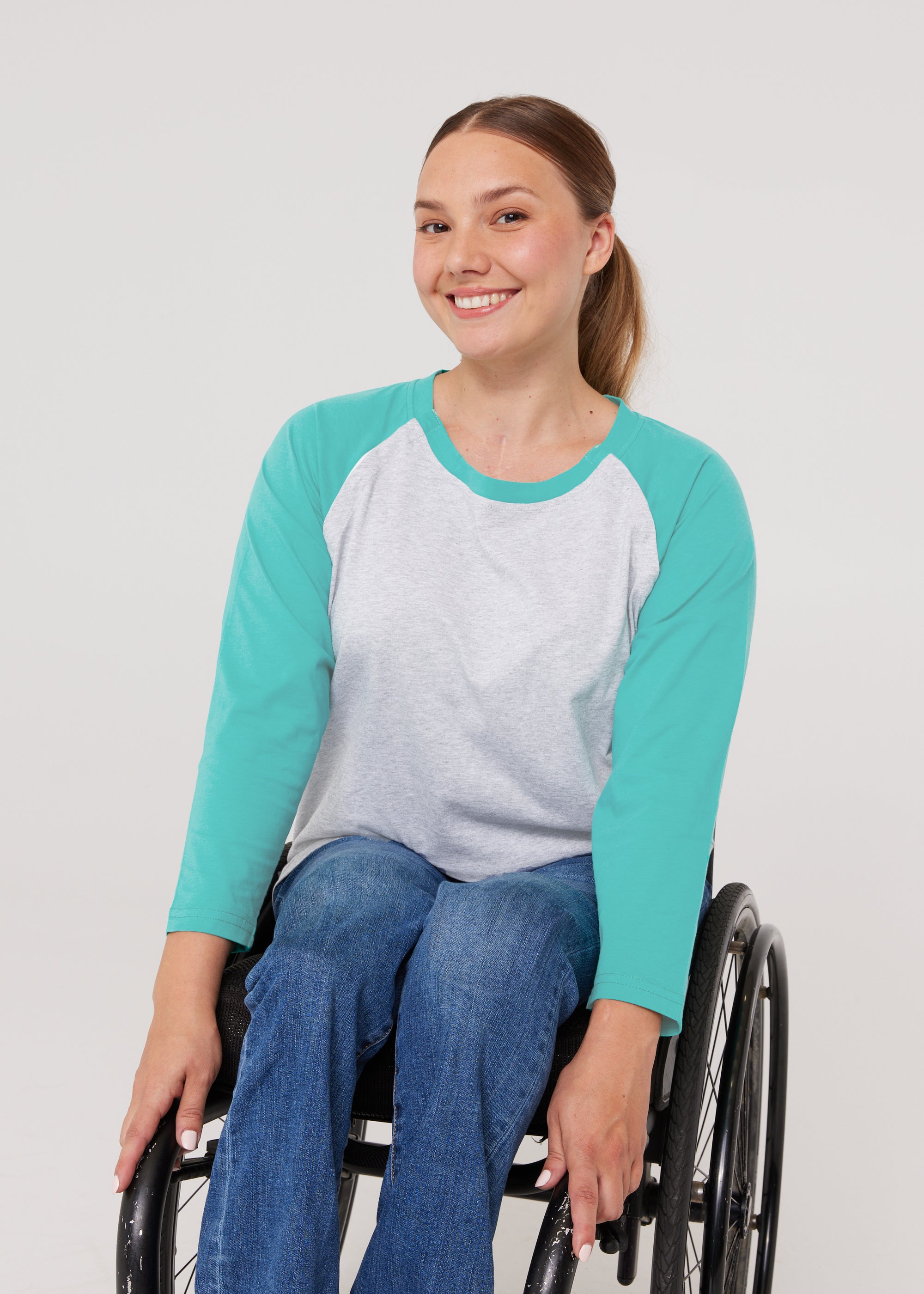Woman in wheelchair wearing teal Adult Raglan Chemo Port Access Tee Shirt