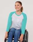 Woman in wheelchair wearing teal Adult Raglan Chemo Port Access Tee Shirt