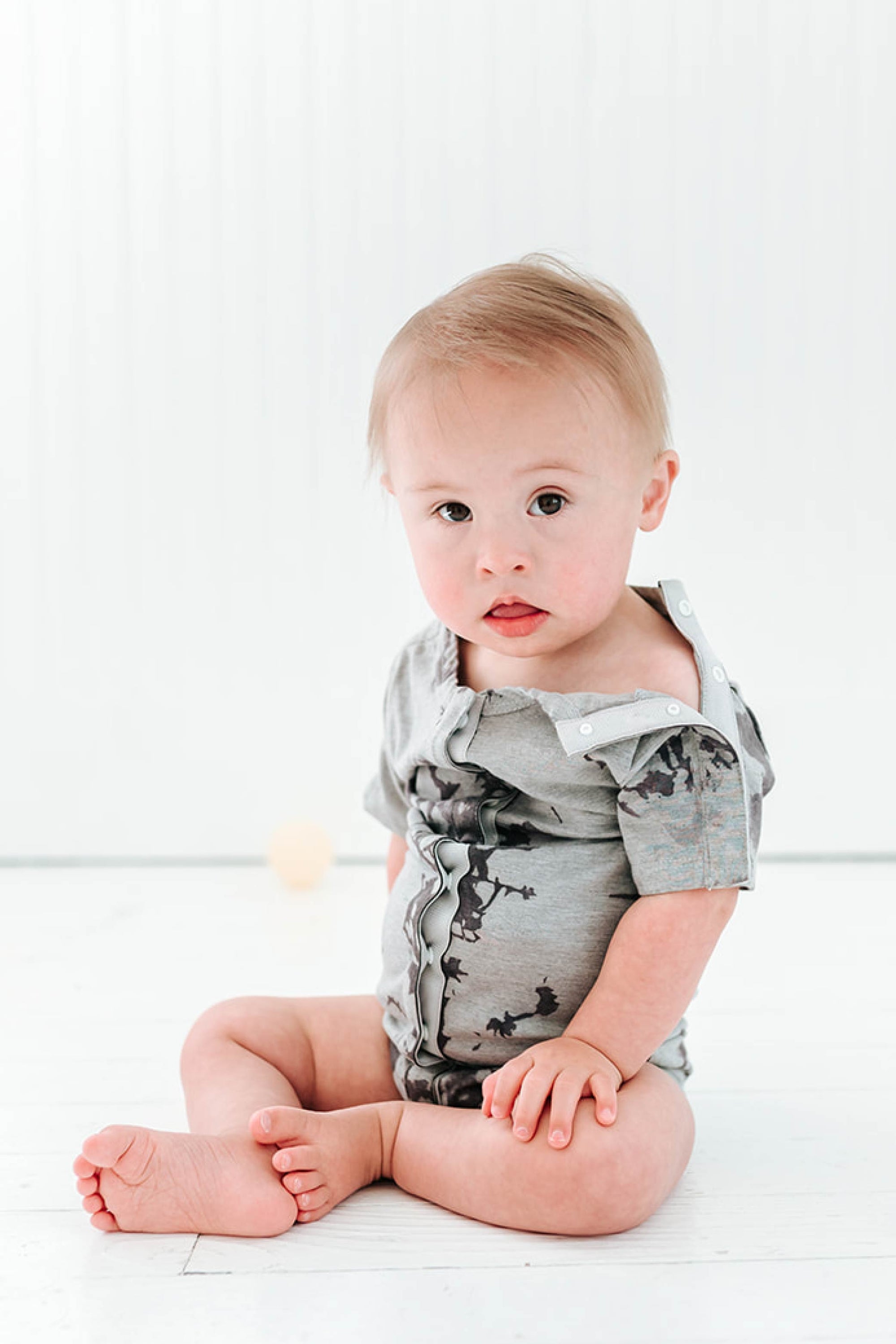Baby boy in tie dye All Access bodysuit with snaps open