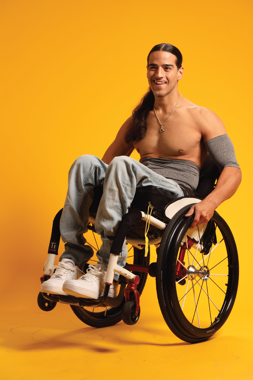 Man in wheelchair wearing gray support sleeve and waistband
