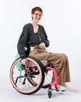 Woman in wheelchair wearing zipper access tee and cargo pant. Text reads "Katelyn is 5'6" wearing a size M."