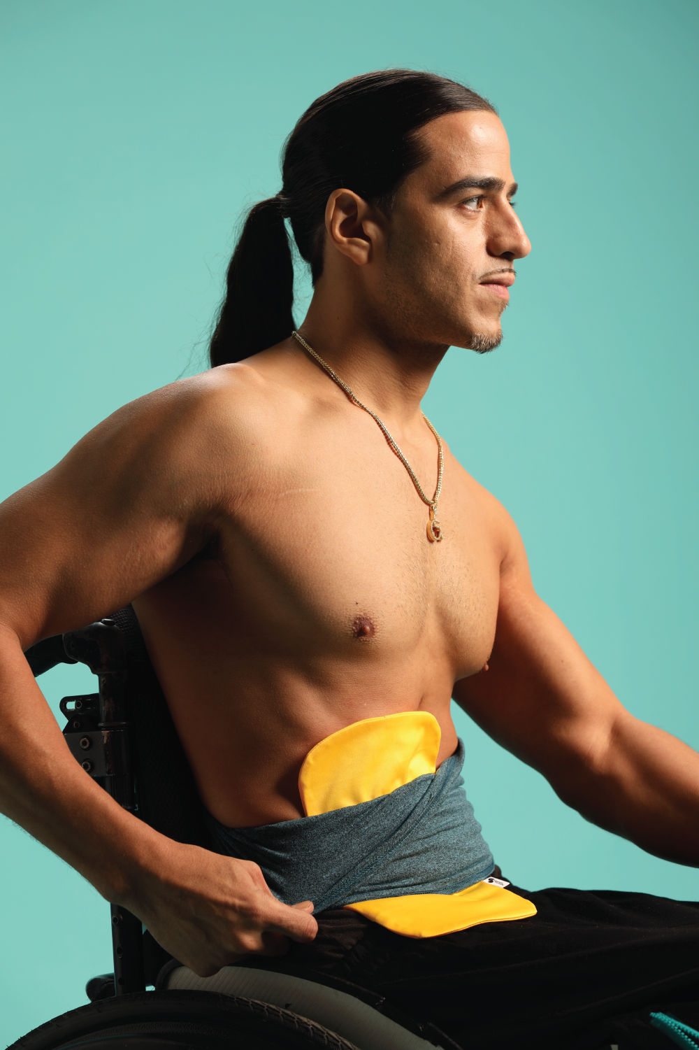 Man wearing Gold Elastic Ostomy bag cover under teal stretch waistband
