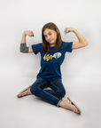 Girl sitting with arms flexed wearing Royal Blue Spoonie for Life G-tube zip shirt with zipper for abdominal access