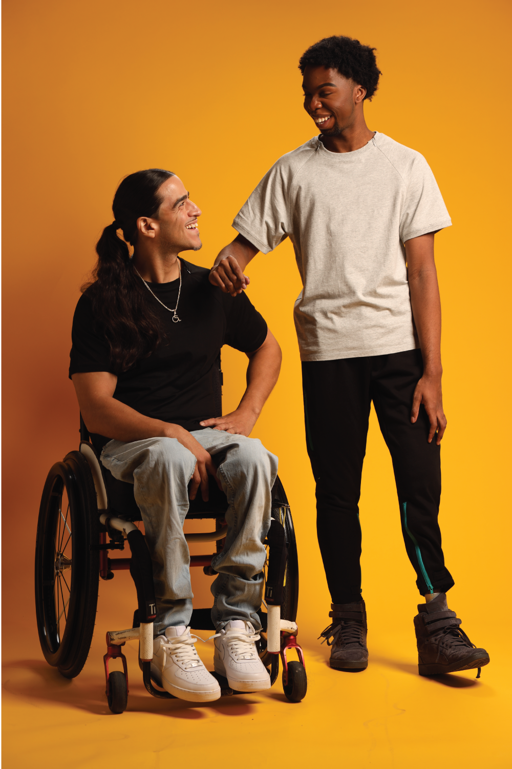Man in wheelchair wearing black Adult Raglan Chemo Port Access Zip Tee Shirt, man standing wearing gray Adult Raglan Chemo Port Access Zip Tee Shirt