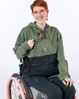 Model wearing Sage Colorblock Hoodie with PICC line coming out of chest zipper. Text reads "Katelyn is 5'6" wearing a size M".