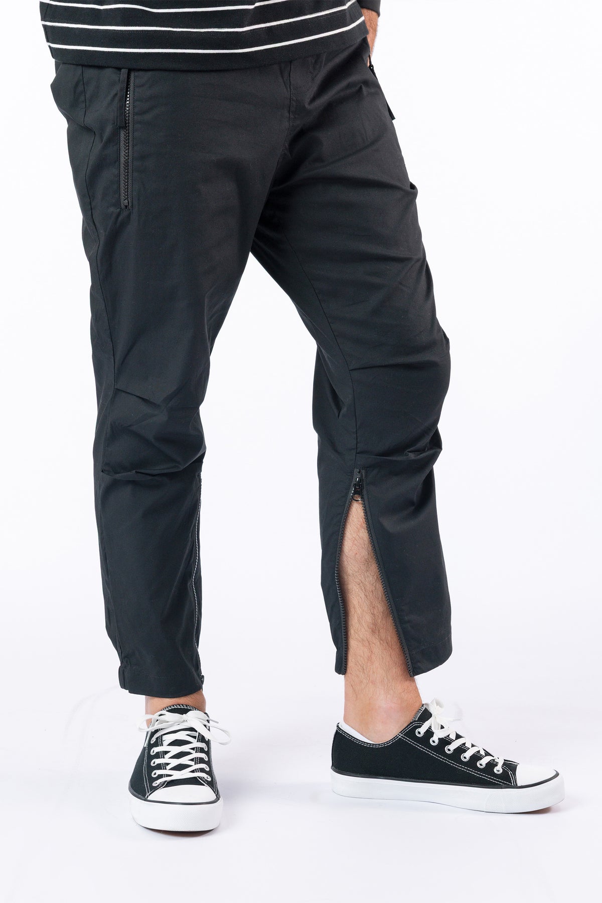 Male model wearing black casual zip pants with ankle zipper open