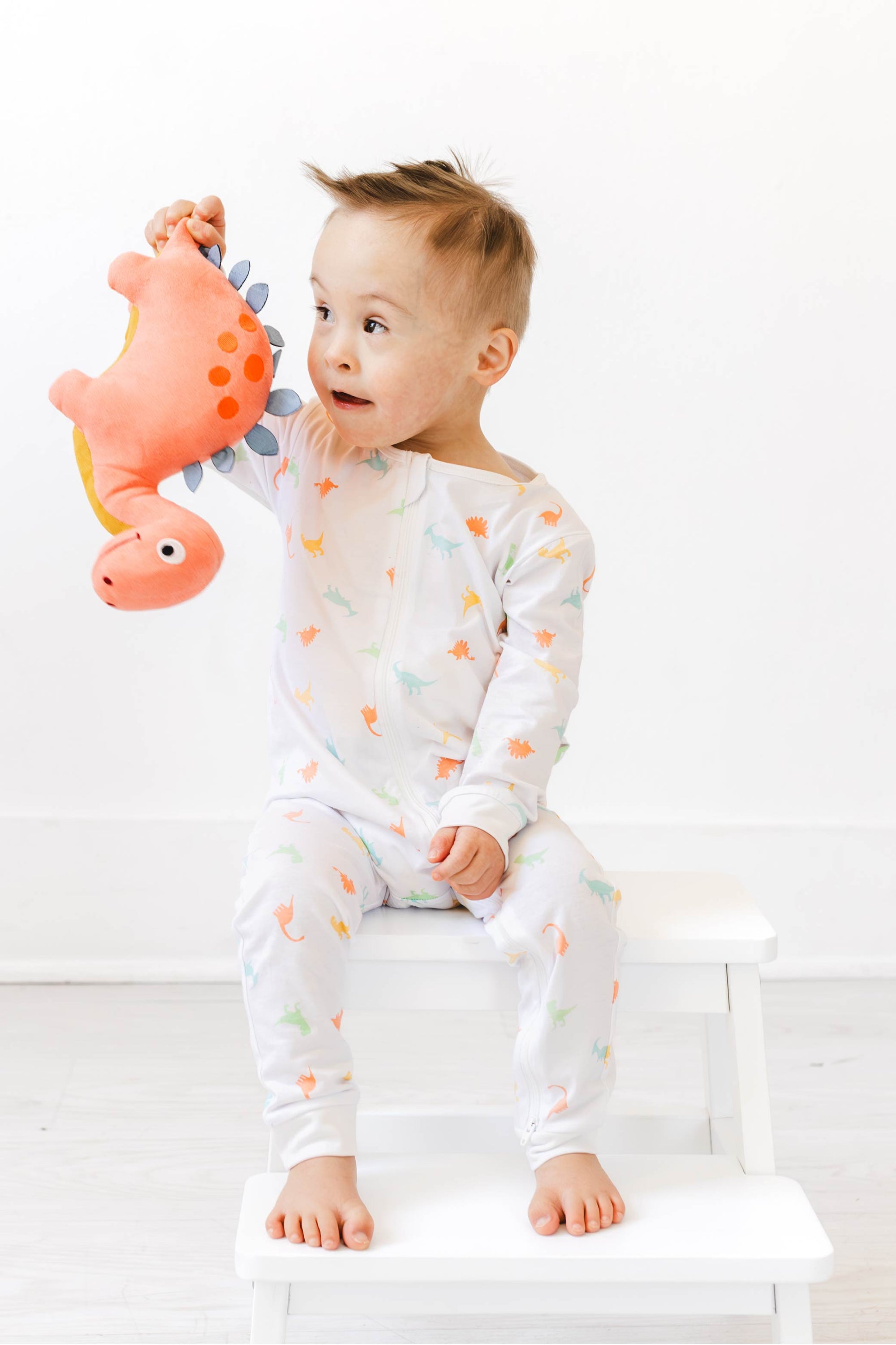 Boy wearing dino g-tube pajamas with stuffed dinosaur