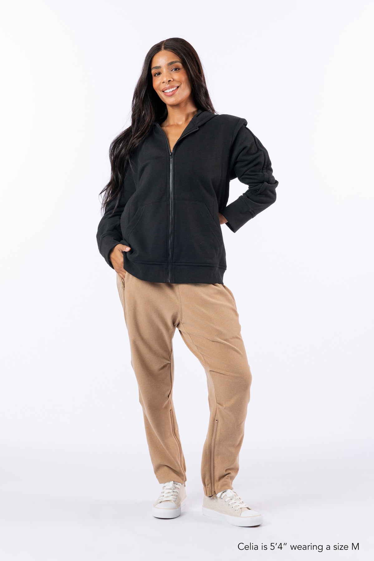 Woman wearing Full Zip Hoodie and Felt Zip Pants. Text reads "Celia is 5'4" wearing a size M".