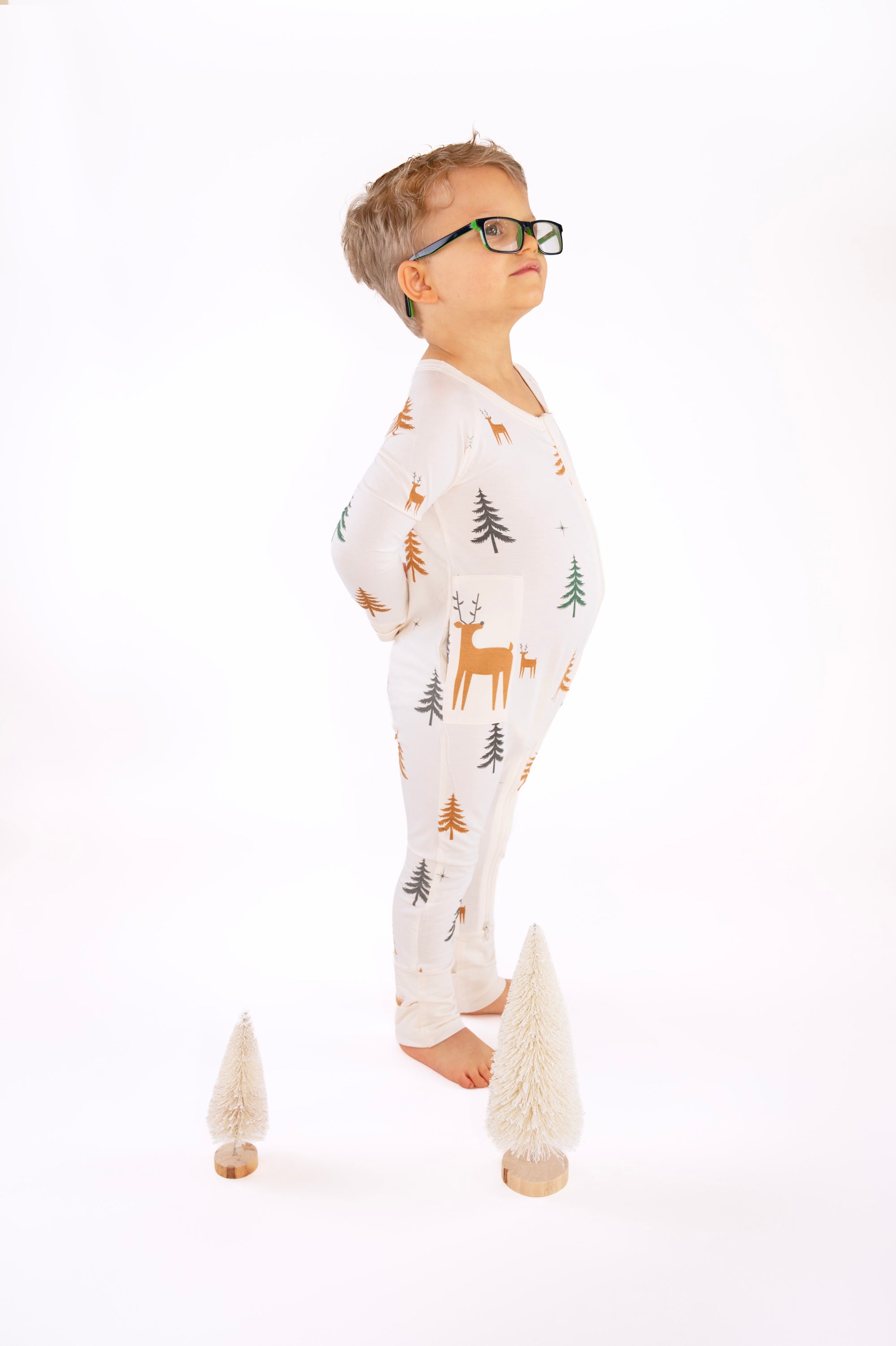 Boy standing in Thru the Trees G-Tube Pajamas with mini tree decorations
