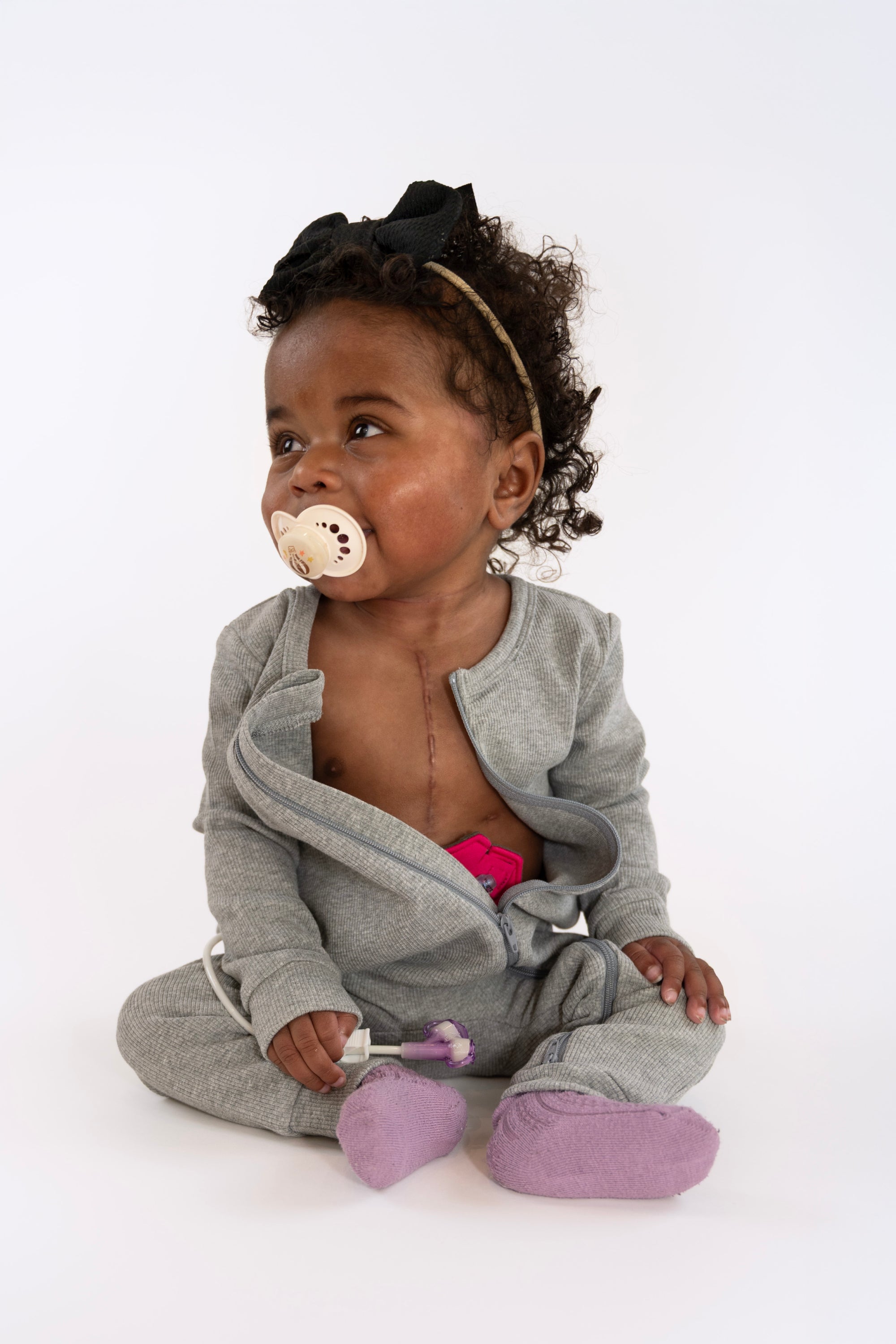 Baby in open Heather Gray Rib G-Tube Pajamas with G-Tube pad showing