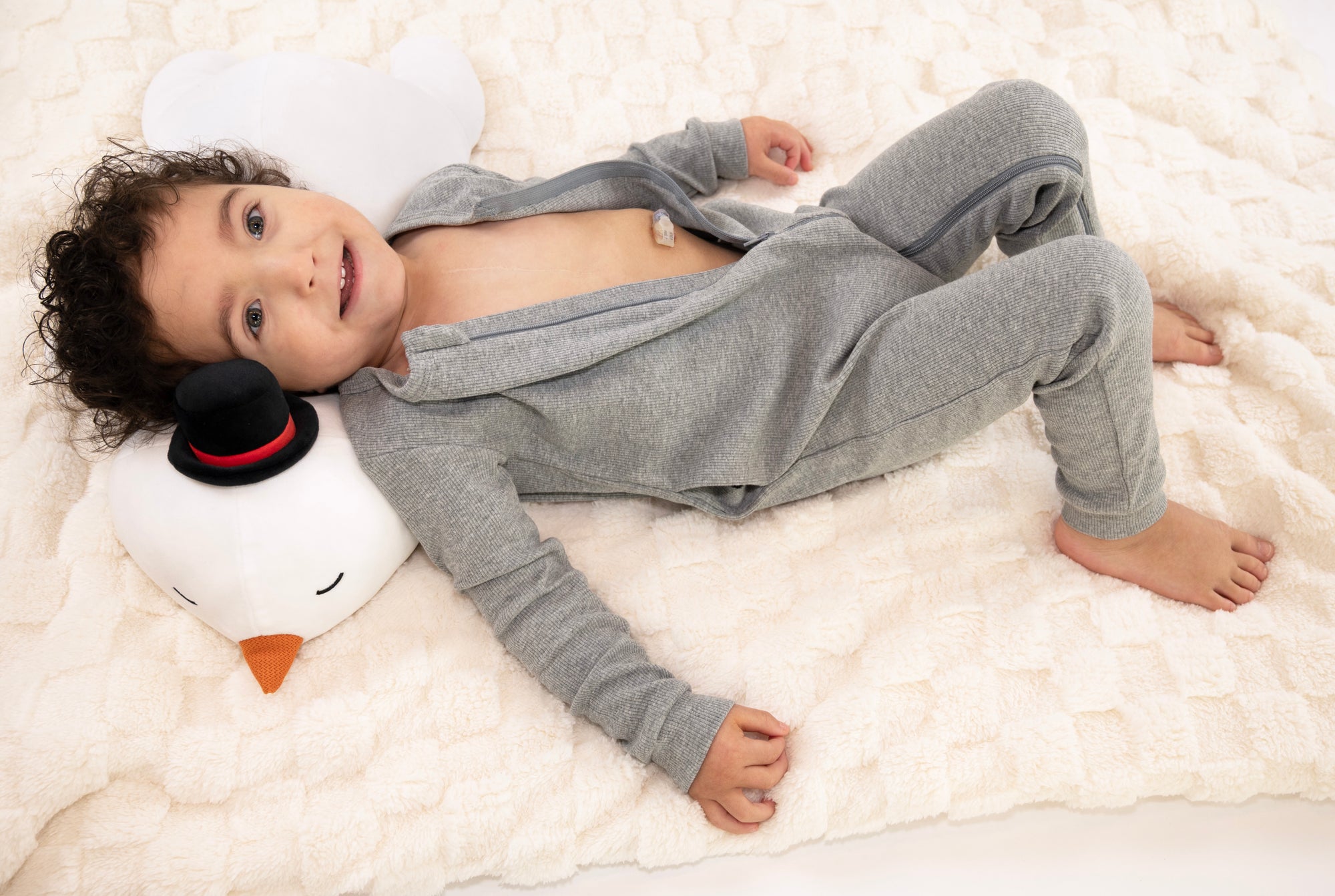 Child wearing open Heather Gray Rib G-Tube Pajamas lying down