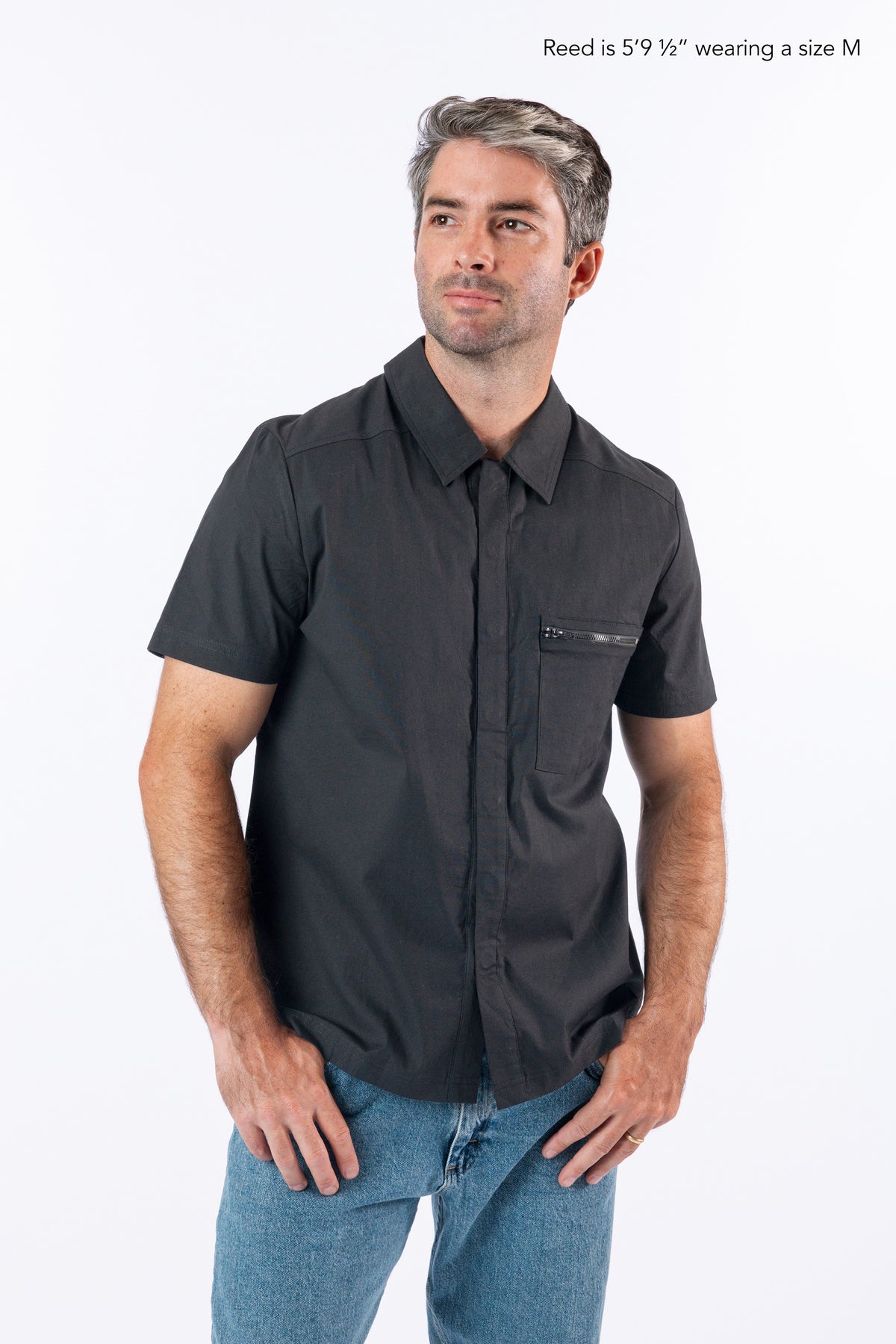 Male model wearing black magnetic dress shirt. Text reads "Reed is 5'9 1/2" wearing a size M".