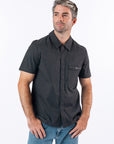 Male model wearing black magnetic dress shirt. Text reads "Reed is 5'9 1/2" wearing a size M".
