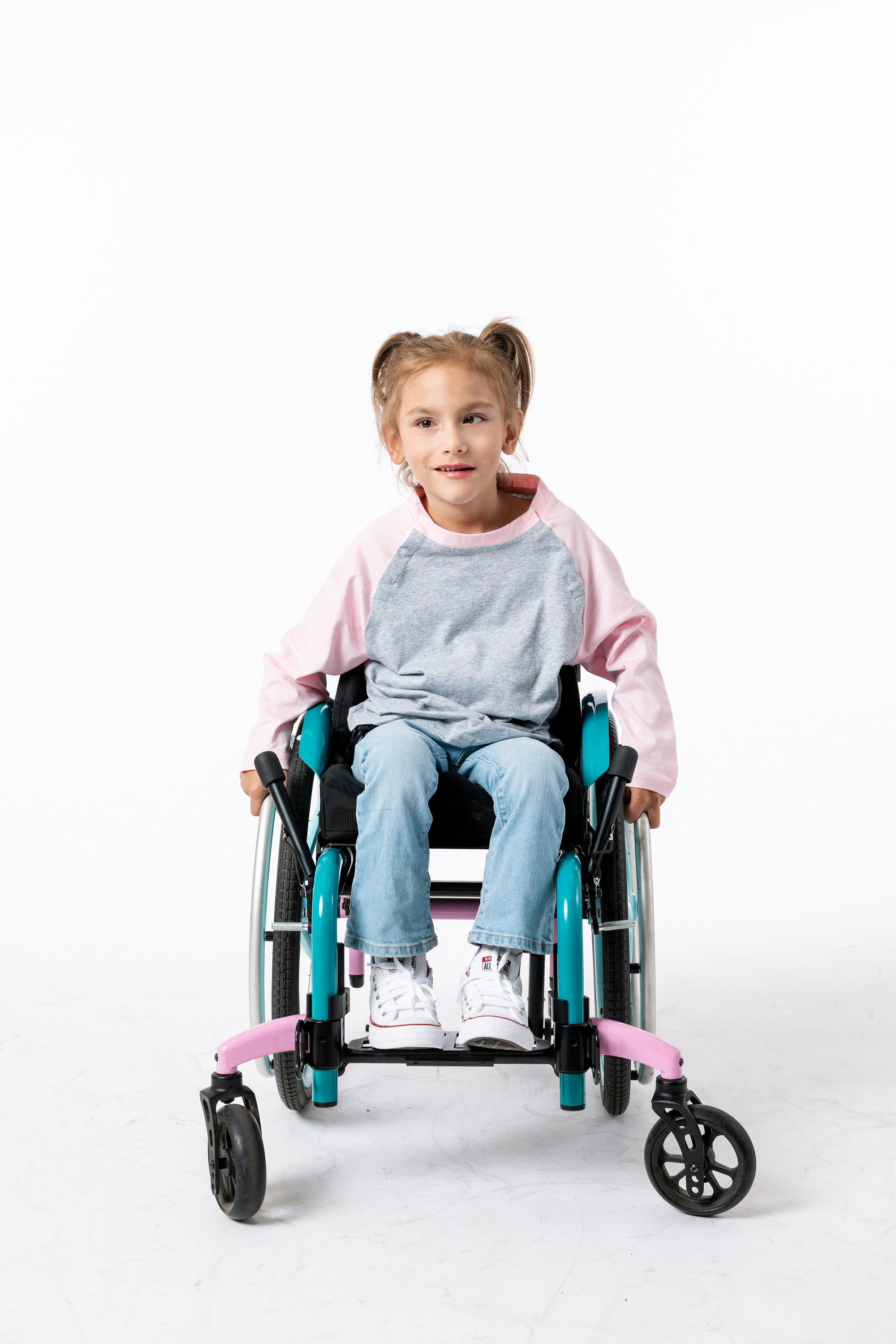 Gracie  in a wheelchair wearing a pink Raglan Access Tee on a white background