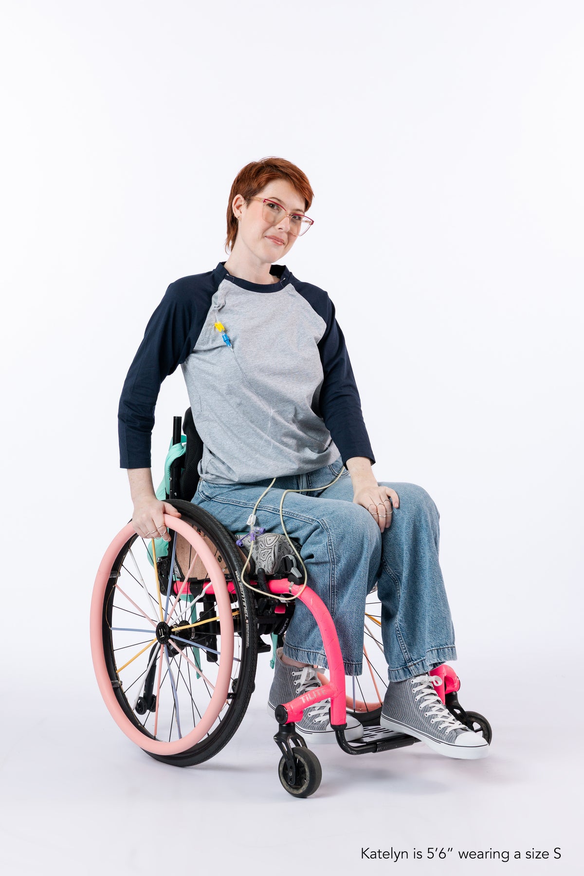 Woman in wheelchair wearing Raglan Access Tee. Text reads "Katelyn is 5'6" wearing a size S".