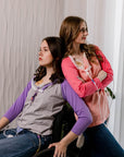 One woman standing in Sunset Raglan Colorblock Access tee, one woman in wheelchair in purple Raglan Access Tee, both showing chest port access
