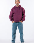 A man modeling a plum zipper access hoodie paired with blue jeans and black-and-white sneakers, against a plain white studio background. Text reads "Reed is 5'9 1/2" wearing a size M".