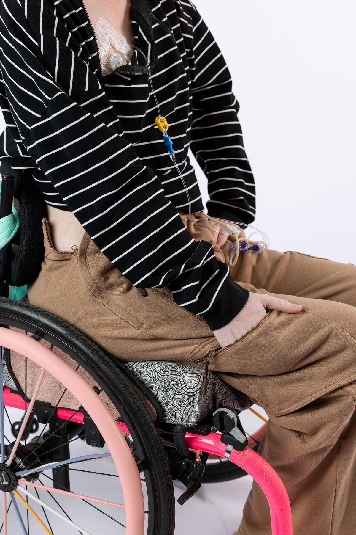 Model putting hand in pant pocket, showcasing front pocket of wheelchair pants