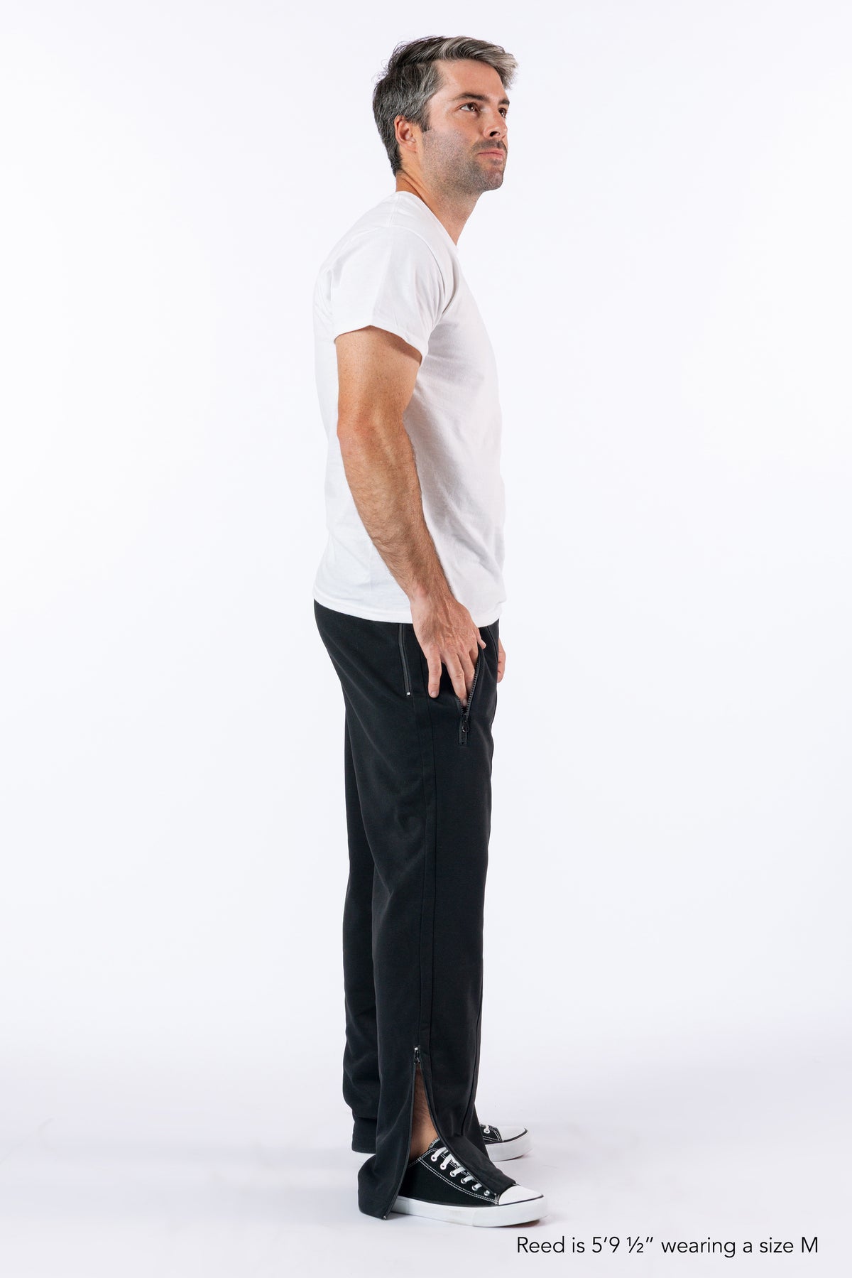 Male model showing open ankle zipper. Text reads "Reed is 5'9 1/2" wearing a size M".