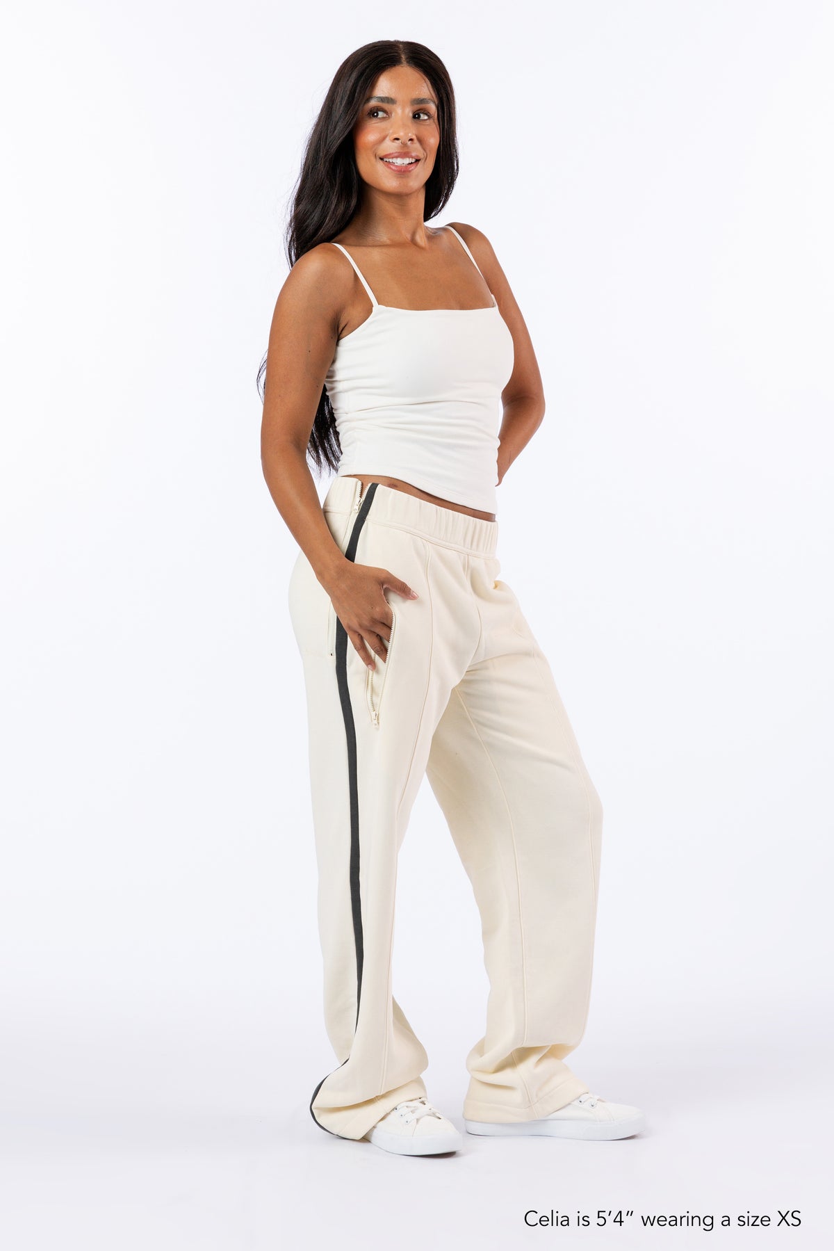 Female model wearing Vanilla Zipper Access Pants. Text reads "Celia is 5'4" wearing a size XS".