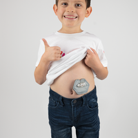 Boy holding up shirt to display gray g-tube pad in use