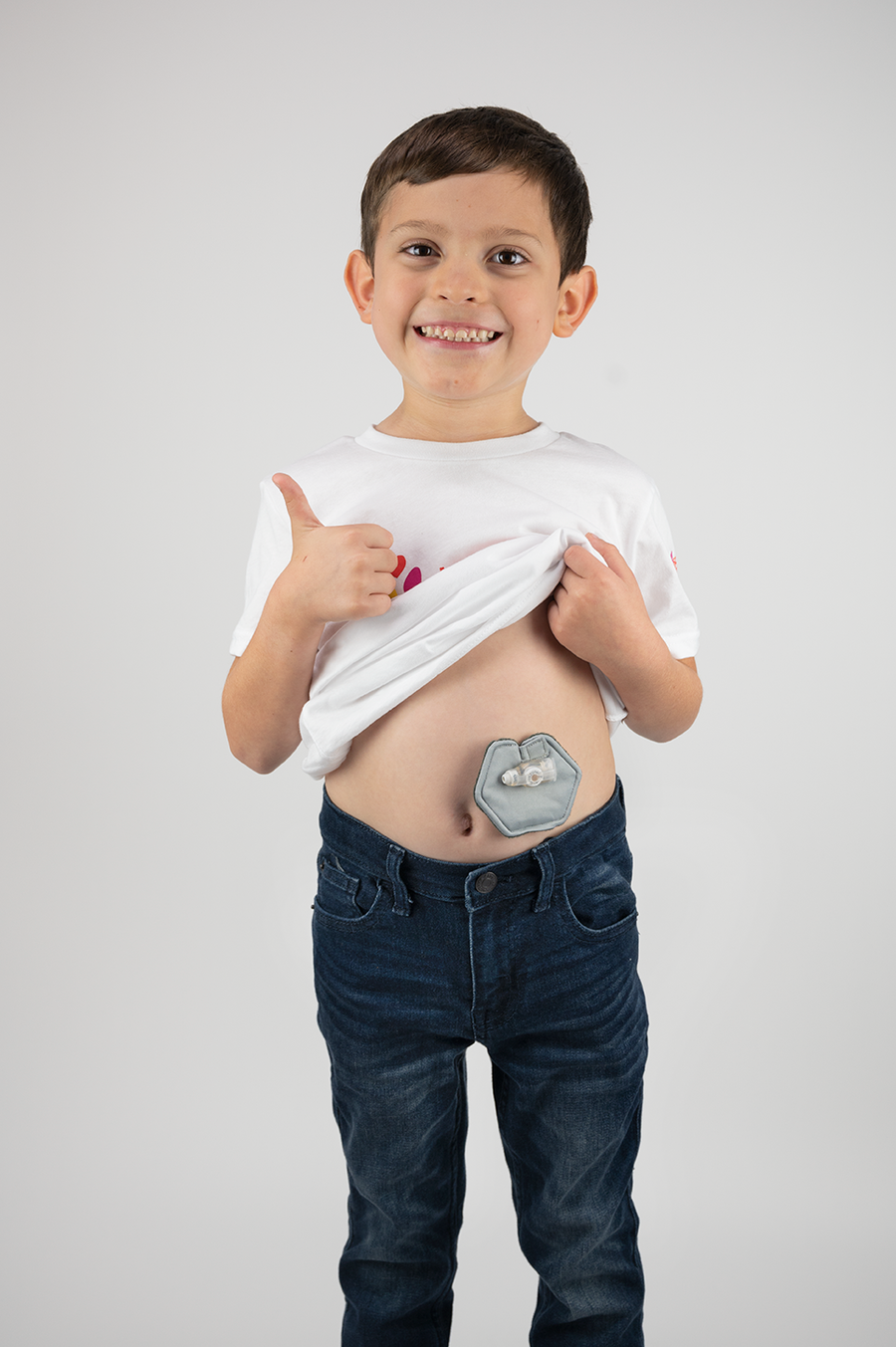 Boy holding up shirt to display gray g-tube pad in use